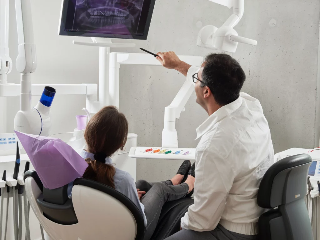 Male dentist pointing to diagram with patient.