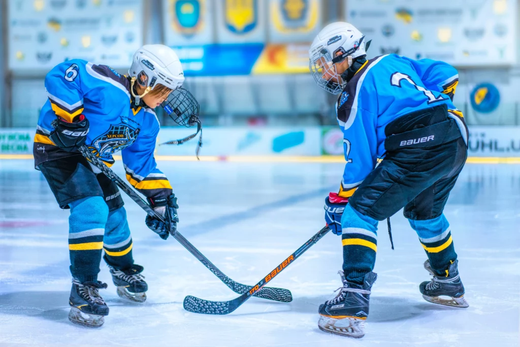 Two boys playing hockey on the ice.