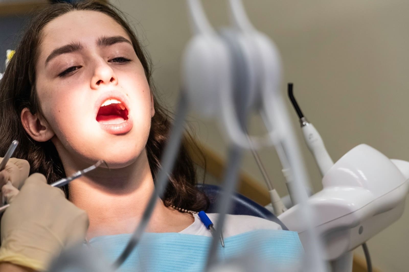 Close-up of a focused toddler with pigtails, wearing a pink sweater, actively brushing her teeth with a yellow toothbrush. This promotes establishing positive early dental habits and proper brushing technique for young children.