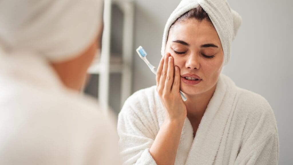 Detailed close-up showing a dental professional's gloved hands (in blue nitrile gloves) demonstrating the use of dental floss on a patient's mouth. The floss is positioned near the teeth to illustrate correct flossing technique for plaque removal and interdental cleaning. Focuses on oral hygiene education and preventative dental care.